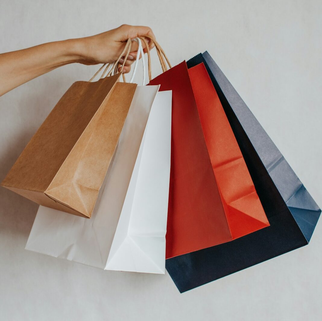 Hand holding colorful shopping bags against a light background